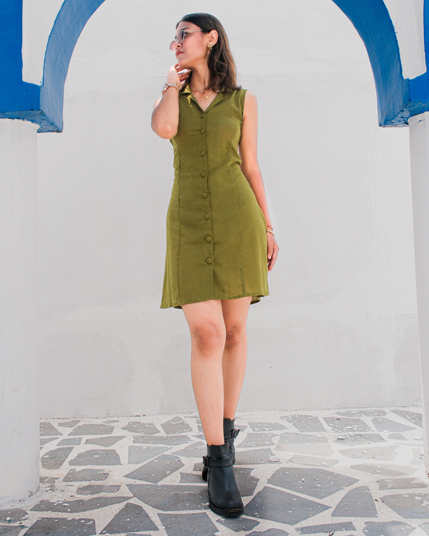 women in a olive green mini shirt dress standing in a sunlit roof top