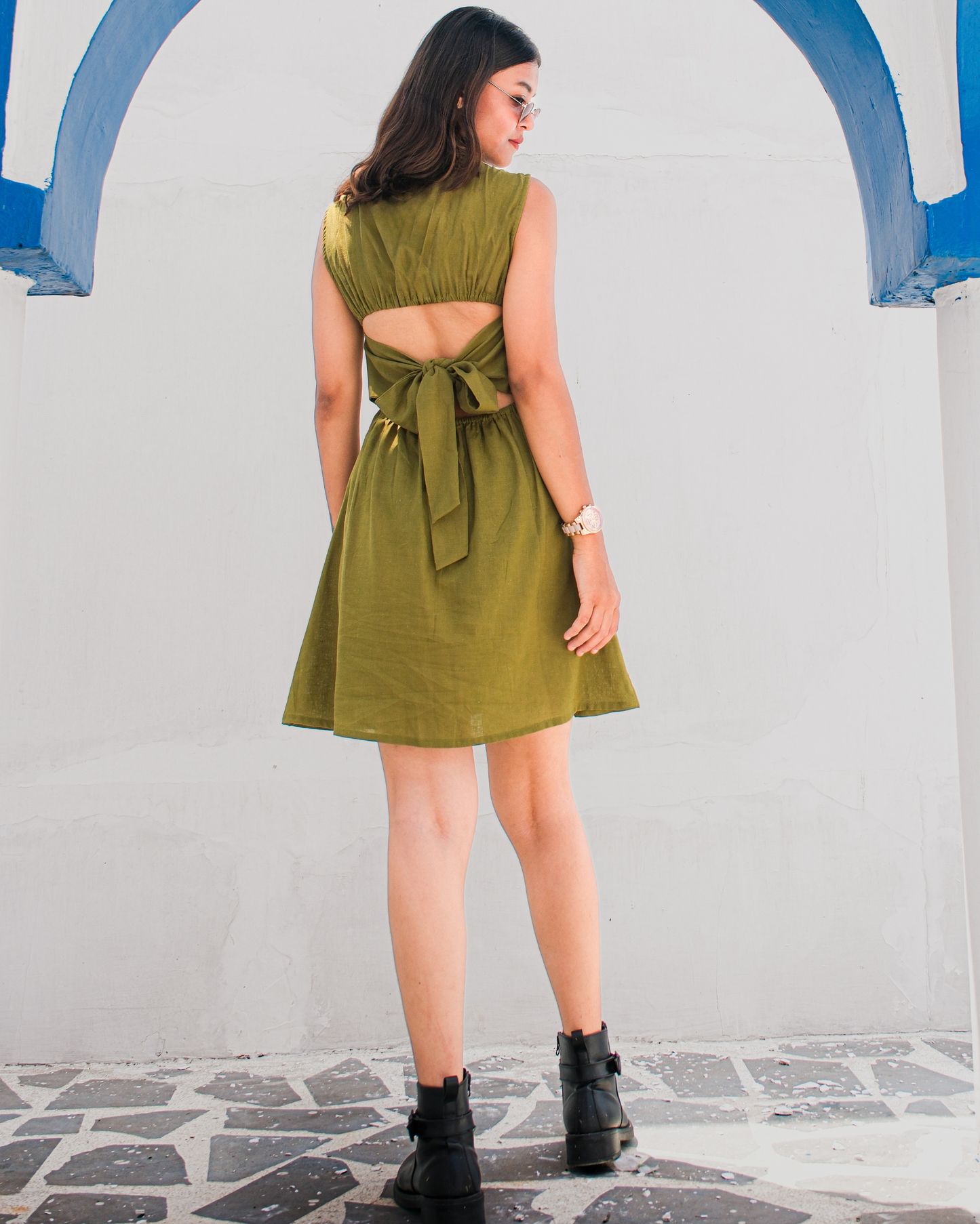 women wearing a olive green cotton linen dress that has back cutout and tie up details from brand moodora