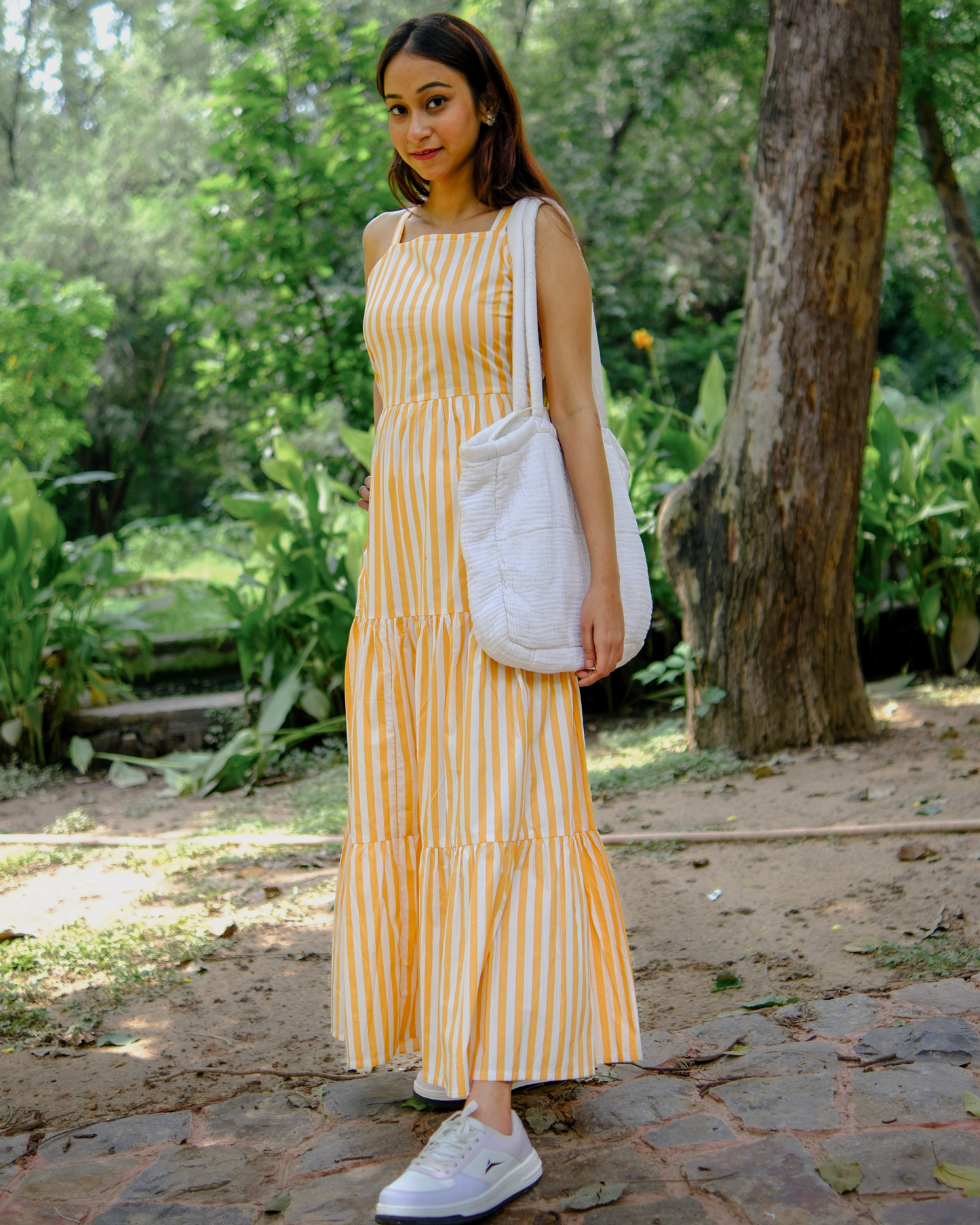 women wearing a pure cotton white and orange stripe dress by moodora standing in a park at a summer afternoon.