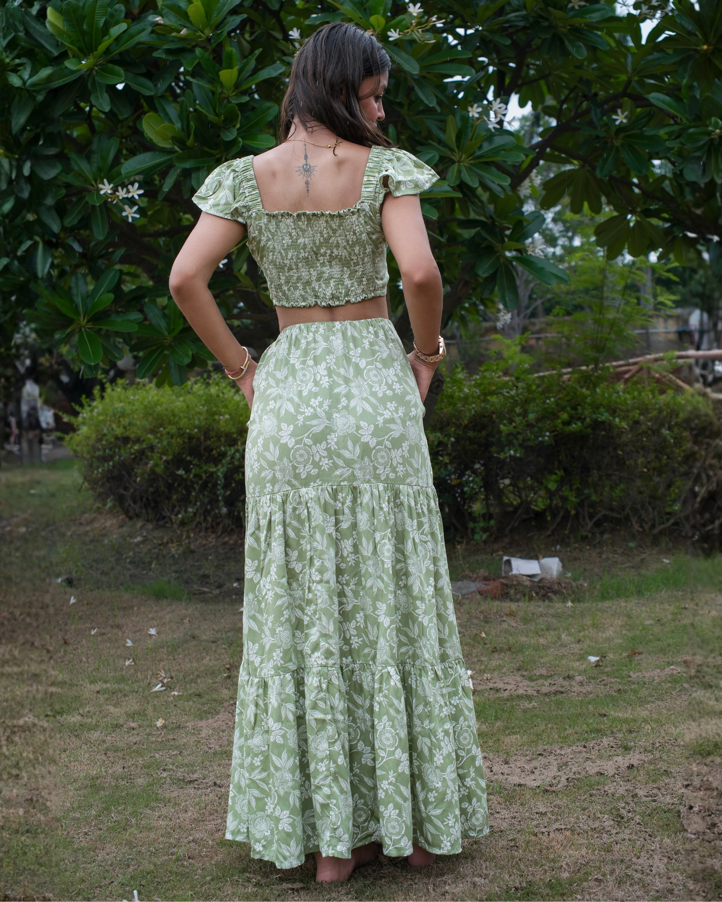 Woman wearing a green floral co-ord set standing outdoors with trees in the background.
