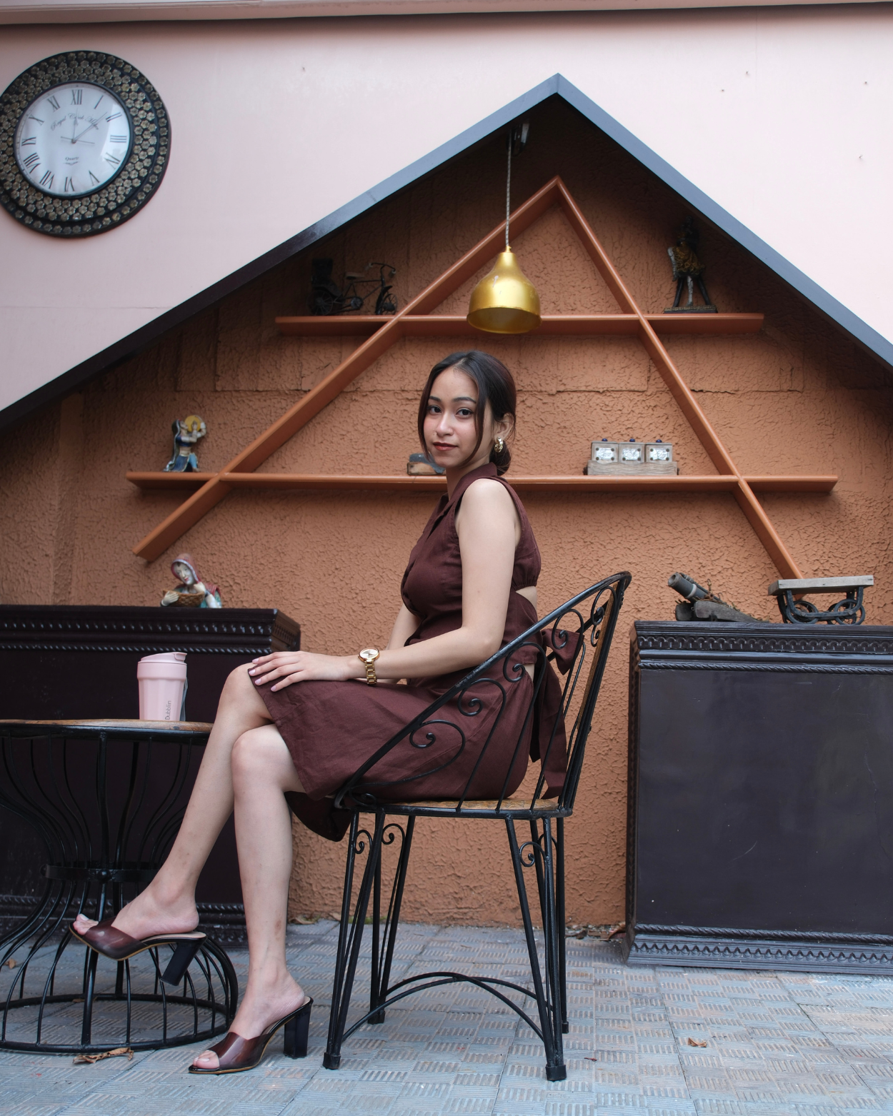 Woman in a brown dress sitting on a chair in a cafe enjoying her coffee with confidence.